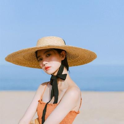 China Handmad Foldable Rolled Women Wide Brim Beach Sun Shade Covers Large Natural Flat Surface Wheat Straw Hats Summer Stylish With Long Ribbon Lace-up for sale