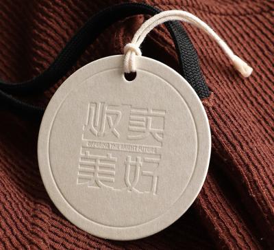 China Sustainable Pure White Round Embossed Swing Tags Custom Clothing Tag Labels Garment Hang Tags for sale