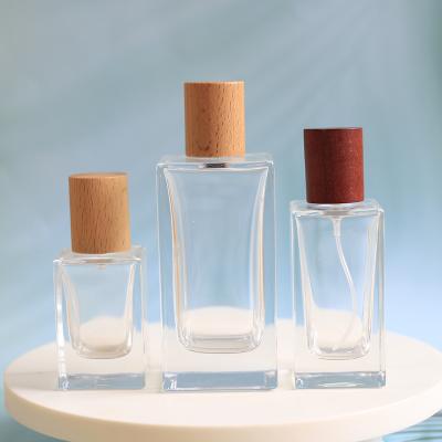 China Square 30ml 50ml 100ml Cosmetic Thick Bottom Clear Glass Perfume Bottles With Wooden Caps for sale