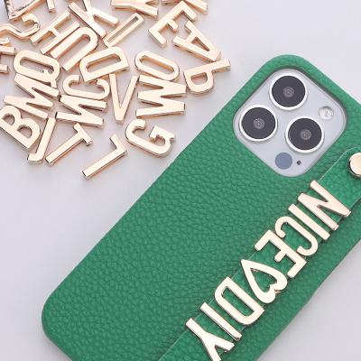 China Leather Phone Case Custom Pebble Leather Strap Phone Case With Letter Charm for sale