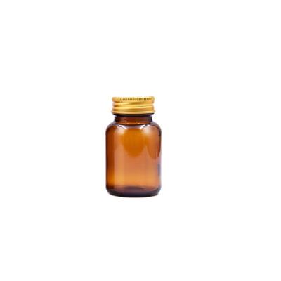 China Eco-friendly Recyclable Wholesale Amber Color 60ml Medicine Storage Capsule Pills Container Glass Bottle With Gold Aluminum Lid for sale