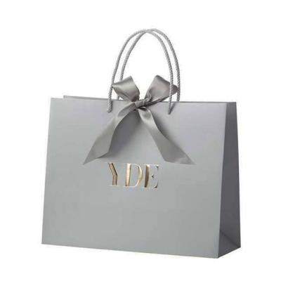 China Disposable Bowknot Sliver Gray Silver Paper Luxury Bag With Embossed Gold Logo By Long Sliver Silk Handle for sale