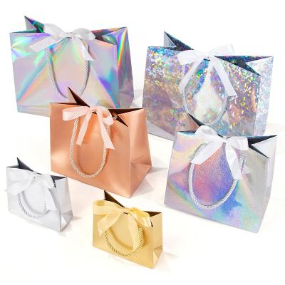 China Recycled Materials Laser Gift Paper Bag Holiday Party Gold And Silver Cardboard Ribbon Small Packaging Paper Bag Can Be Customized Size Printed Logo for sale