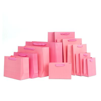 China Recyclable Wholesale Cheap Luxury Disposable Pink Kraft Paper Shopping Gift Bags For Apparel Custom Logo for sale