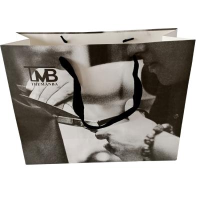 China Competitive Price Customized Brand Recyclable Logo Luxury Boutique Shopping Black and White Pattern Bag Craft Paper with Ribbon Handles for sale