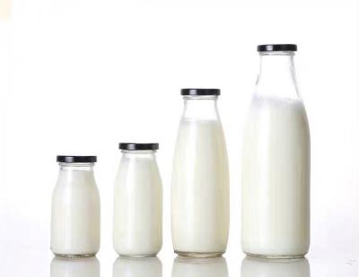 China Viable clear empty glass round milk bottles with lids juice glass bottles for sale