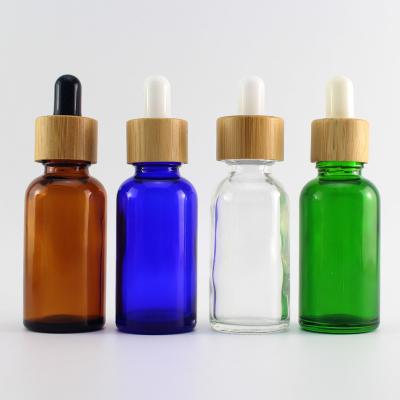 China Essential Oil Cosmetic Liquid Serum Round Shape Glass Dropper Bottle With Bamboo Cap for sale